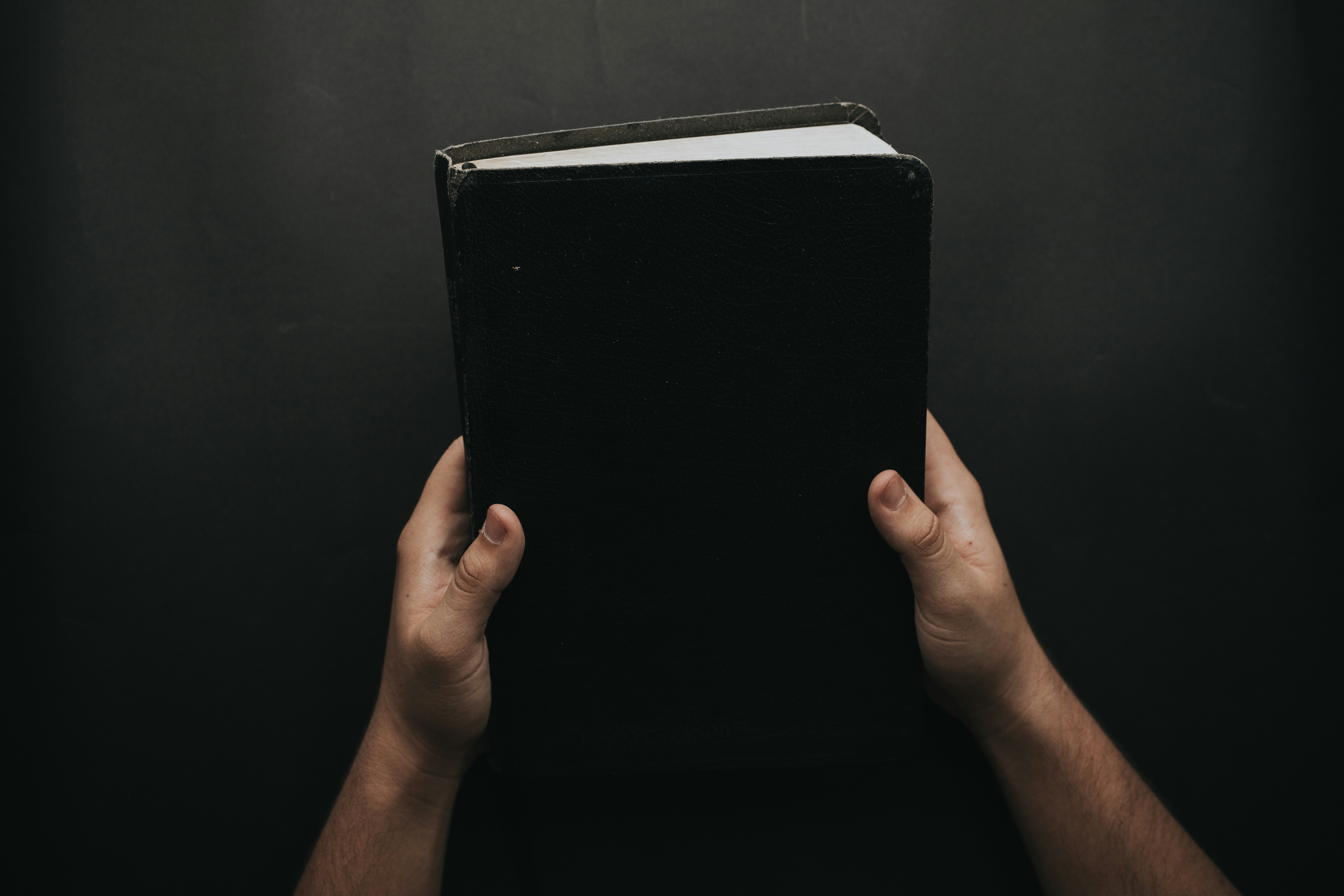 Hands holding a black playbook representing the AR automation guide