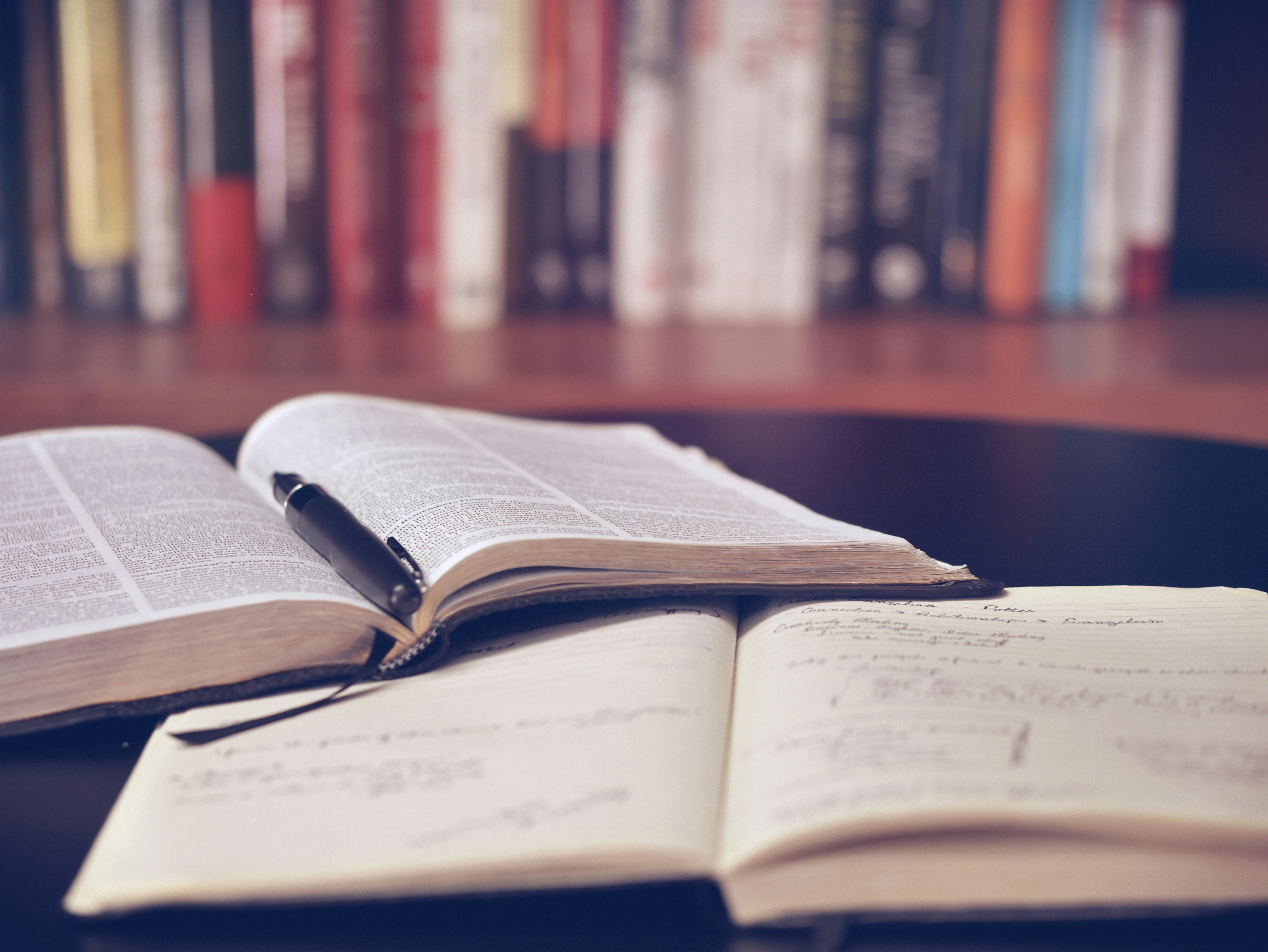 Open books with a pen on a desk, representing research and case study analysis